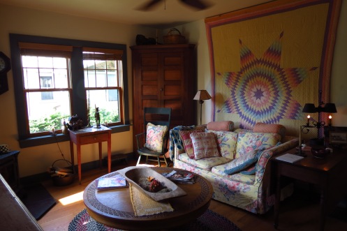 The living room is enlivened by an antique quilt and a round table, made by Susan's father.